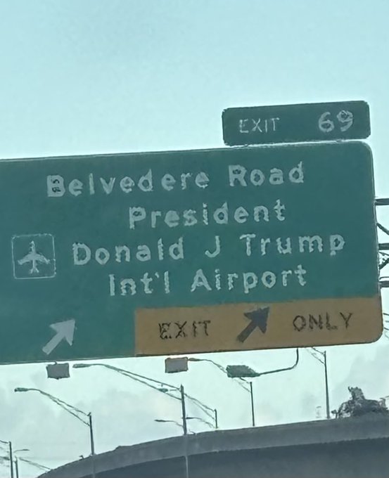 Green highway sign directing traffic to 'Belvedere Road' and 'President Donald J Trump Int'l Airport' at Exit 69, with an airport symbol and 'EXIT ONLY' indicator.