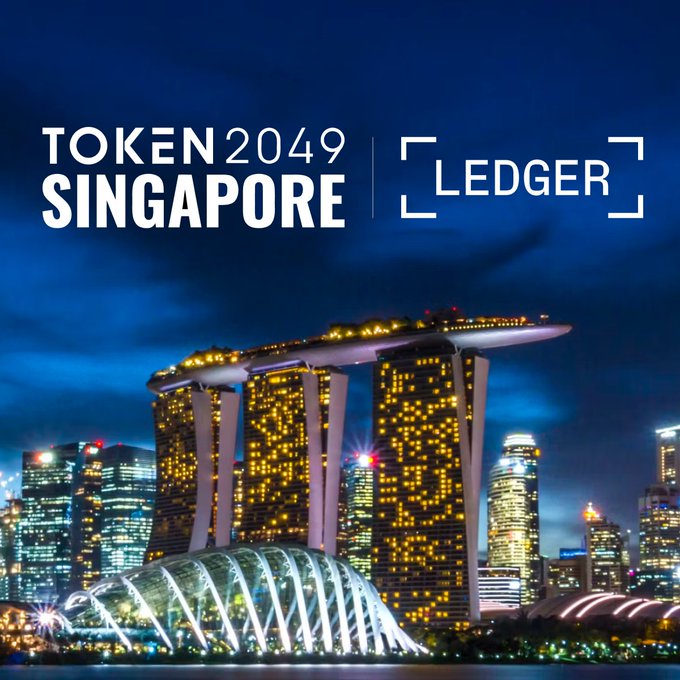 The image features a nighttime skyline of Singapore's Marina Bay area, showcasing the iconic Marina Bay Sands hotel and other illuminated skyscrapers, overlaid with the text "TOKEN 2049 SINGAPORE | LEDGER."

The promotional graphic ties into Ledger's presence at the Token2049 crypto conference in Singapore, announcing their attendance and activities at the event.