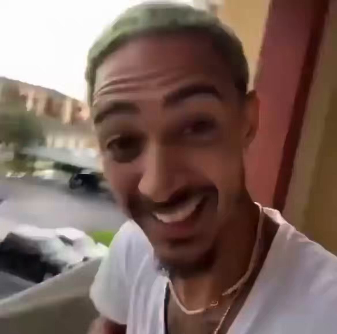The image shows a man wearing a white t-shirt, standing outside of an apartment building with his face displayed for the camera. The man has green hair, making him look very unique and interesting. He is smiling at the camera, giving off a happy vibe. A caption below the photo states that XRP is going from $3.66 down to just $1.09 in value, creating an exciting opportunity for people who are interested in investing in this digital currency.