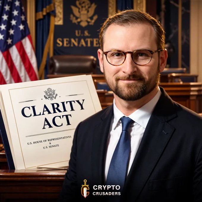 A man with glasses and a beard in a suit standing in front of a U.S. Senate backdrop, holding a document labeled 'CLARITY ACT' with a 'CRYPTO CRUSADERS' watermark at the bottom.