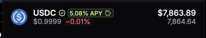 The image displays a crypto portfolio entry for USDC showing a balance of $7,863.89 (with a reference value of 7,864.64) priced at $0.9999, down 0.01%, and earning a 5.08% APY (indicated by a circular arrow icon). This matches the post, where the $7,863 figure refers to the USDC balance that was received as an unsolicited token and is now being given away to the community.