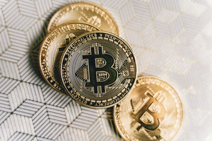 A close-up of physical Bitcoin tokens, with the text "BITCOIN DIGITAL DECENTRALIZED PEER TO PEER" visible on one of the coins.