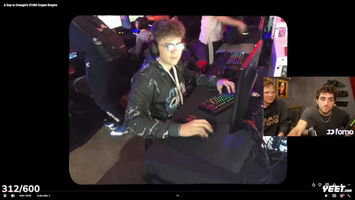 The image shows an online gaming environment with two people playing against each other while wearing headsets. One person is sitting at a table in front of a computer, and another person is standing next to them. A third person can be seen on the right side of the frame as well. The scene appears to be set up for a game of "Dookey Dash", which may have a significant financial reward.