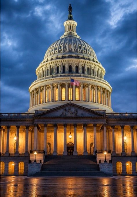 A nighttime photograph of the United States Capitol building with its illuminated dome and columns, an American flag flying, and a dramatic cloudy sky overhead.