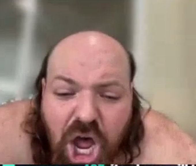 A close-up of a bald, bearded man with his eyes closed and mouth open, appearing to shout or speak emphatically.