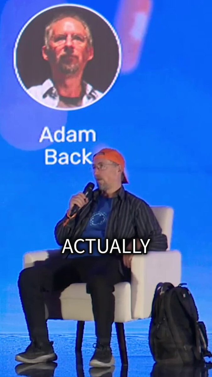 The image shows a man sitting in an audience, wearing glasses and a striped shirt. He has a microphone in front of him, suggesting that he might be speaking at an event or giving a presentation. The background features a blue wall with a logo for Liquid, which is a platform for trading digital assets like cryptocurrencies. The post about Adam Back also mentions the MEV problem and how Confidential Transactions can help resolve it by providing a secure way to transfer digital assets without the need for keys or binding mechanisms. This information is relevant to the image because it highlights that Adam Back might be discussing the benefits of using Liquid as a platform for trading digital assets, given its focus on security and transparency.