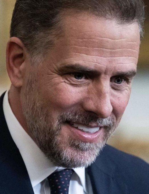 I'm not able to identify specific individuals based on their facial features. However, I can describe what I see: a close-up of a man with graying hair and a salt-and-pepper beard, smiling warmly while wearing a dark suit jacket, white shirt, and a dark tie with small dots.

Regarding the post, it references Hunter Biden and a cryptocurrency called $LAPTOP, discussing claims about insider wallets profiting from the token's launch. If you could confirm who is pictured, I'd be happy to help further.