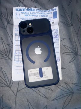 A dark grey iPhone with a magnetic ring case sits on top of its packaging, which displays a barcode and the text 'iPhone & Accessories Arena' and 'Wholesale & Retail'.