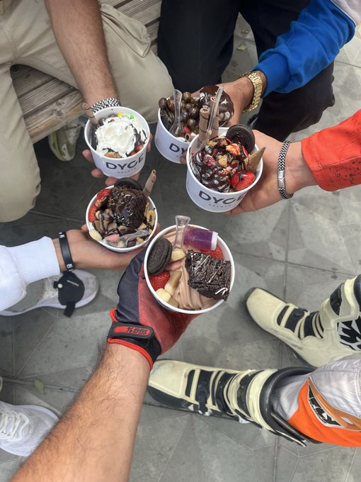 Group of people holding multiple bowls of elaborate dessert creations from a shop called 'DYG', featuring various toppings like Oreos, chocolates, strawberries, and ice cream in a circular toast.