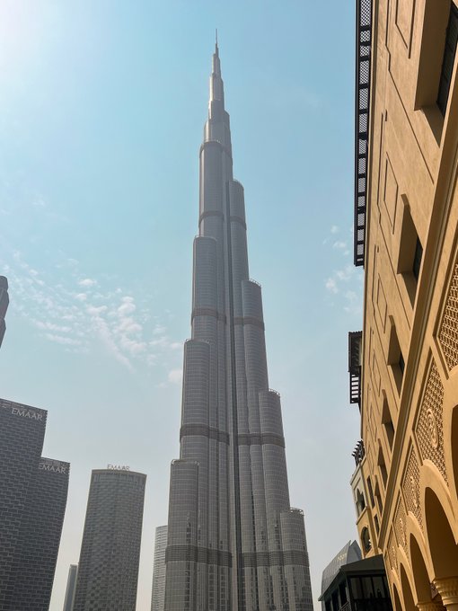 The image features a tall, gray skyscraper with multiple levels, reaching towards the sky. The building's height and architectural design make it an impressive sight against the backdrop of the cityscape. In the foreground, there are several other buildings that contribute to the urban environment. The caption provided seems unrelated to the main subject matter - the skyscraper. It could be a random thought or statement about the city or another topic entirely.