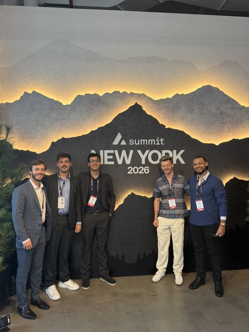 Five men in business casual attire pose together in front of a 'Summit New York 2026' backdrop featuring a mountain graphic.