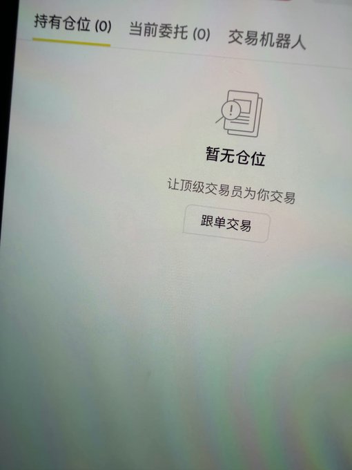 A photograph of a Chinese trading interface screen showing tabs '持有仓位(0)' (Positions), '当前委托(0)' (Current Orders), and '交易机器人' (Trading Bot), with a message '暂无仓位 让顶级交易员为你交易' (No positions, let top traders trade for you) and a '跟单交易' (Copy Trade) button.
