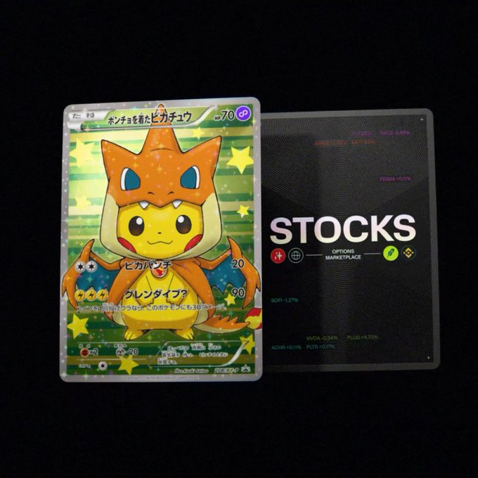 A Japanese Pokémon trading card featuring Pikachu wearing a Charizard costume ("ポンチョを着たピカチュウ") placed next to a black card displaying the word "STOCKS" with financial ticker symbols.