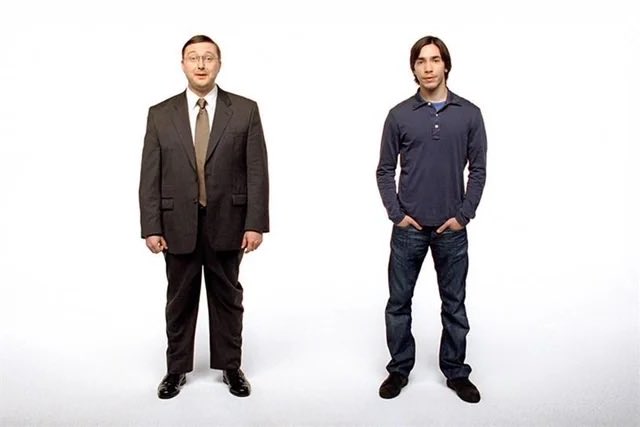 A promotional photo showing two contrasting figures side by side: a middle-aged man in a formal business suit on the left and a younger man in casual jeans and a polo shirt on the right.