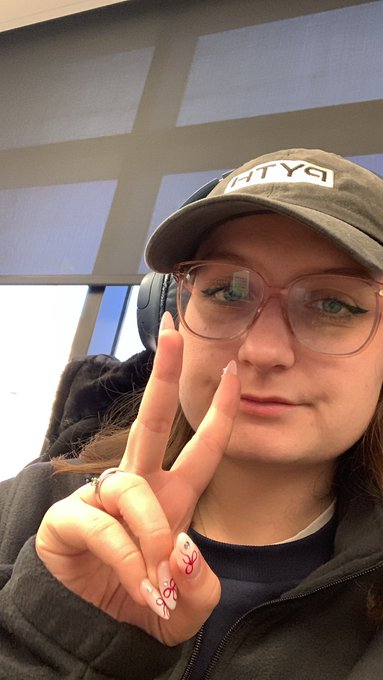 A young woman wearing a "PYTH" cap flashes a peace sign while sporting stylish glasses and decorated nails, posing at her office. The image perfectly captures the post's vibe of being geared up and ready to build while repping the PythNetwork brand.