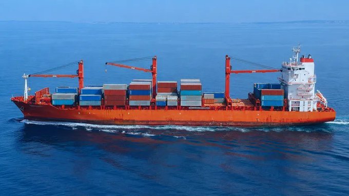 A red and orange container ship loaded with shipping containers sails across the open sea.