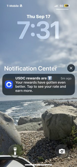 An iPhone lock screen displays the time "7:31" on Thu Sep 17 with a coastal background; a Notification Center alert from Coinbase reads "USDC rewards are up. Your rewards have gotten even better. Tap to see your rate and earn more."