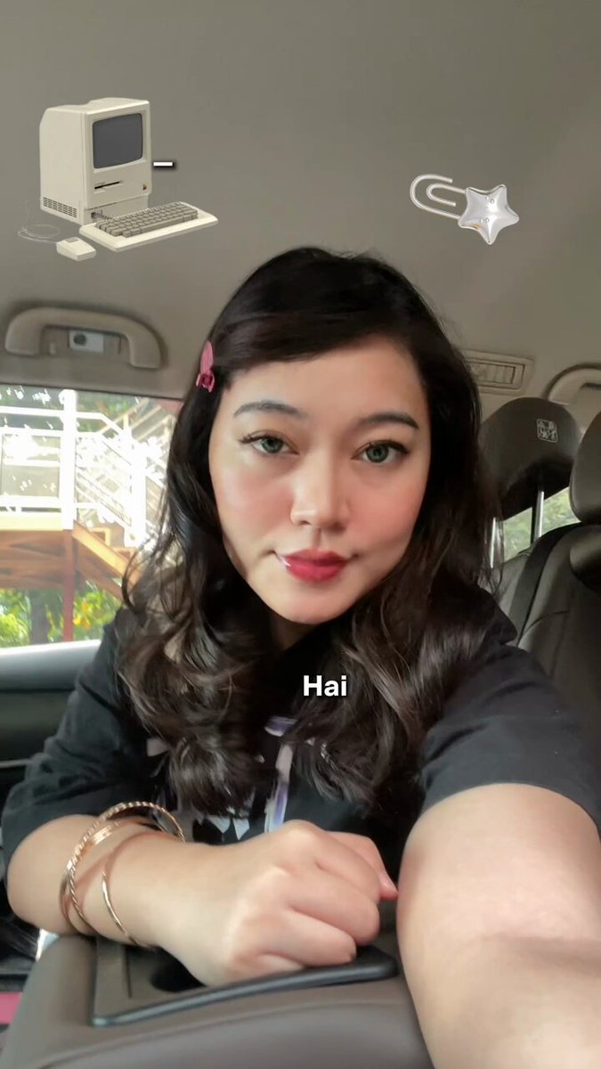 The image shows a woman wearing a black shirt sitting inside a car while posing for a photo with her arm resting on the back of the seat and a star decoration above her head. The caption below the image provides information about an Indonesian community, stating that they want their talents to be recognized worldwide. This suggests that the woman in the photo might have been taken during or just after this event, as she is captured in a moment where her surroundings are connected to the global issue being addressed.