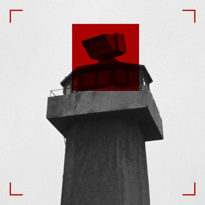 A black-and-white photo of a watchtower with its upper cabin highlighted in red, framed by red targeting brackets.