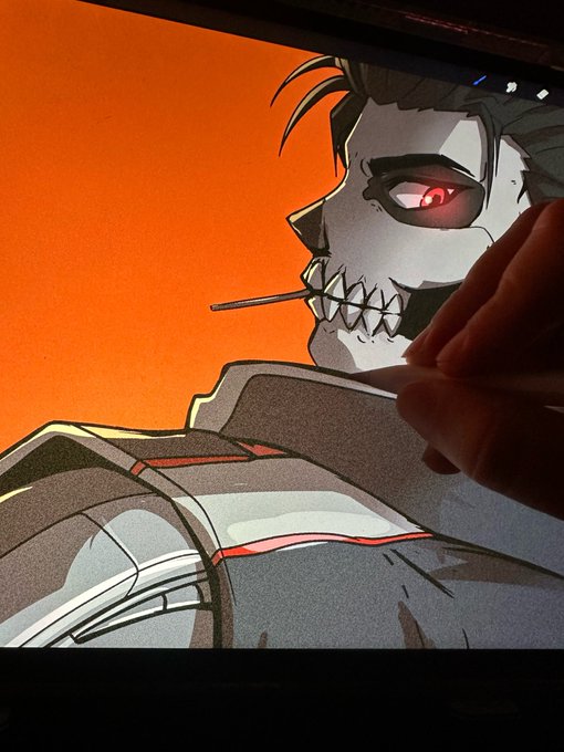 The image shows an artist's hand working on a digital drawing of a menacing anime-style character with a skull-like grinning face, glowing red eye, and spiked teeth, holding a stick in their mouth against a vibrant orange background. The artwork connects to the post as a work-in-progress illustration being created, fitting the caption about always drawing and cooking something new for the artist.