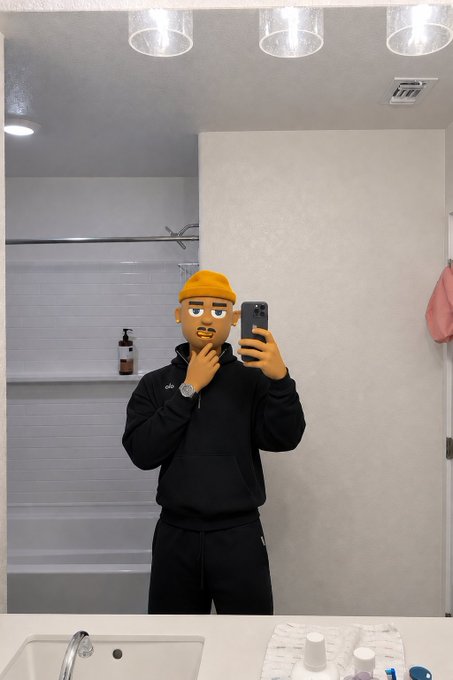A mirror selfie of a person wearing a black hoodie and a yellow beanie, with a cartoon face emoji covering their actual face.