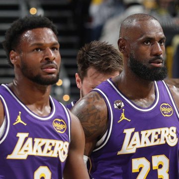 Two Los Angeles Lakers players wearing purple jerseys with "LAKERS" branding and a "bibigo" sponsor patch stand together, with the player on the right wearing number 23. The image relates to the post as it appears to show LeBron James (#23) and his son Bronny James, highlighting the reportedly fading prospect of them sharing an NBA court.