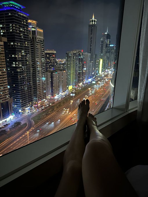 The image shows a person's feet resting on a window sill, with their legs crossed over each other. The scene takes place at night, looking out onto a city skyline filled with tall buildings. The photo has been edited or filtered to give it a dreamy and artistic appearance, making the viewer feel as if they are standing right there in the middle of the city.

The post features an image of a person's feet on their lap, along with some text that reads "Good Night Web3 Good night @Polymarket Fam Good night @base Builder Creator active". This suggests that the photo might have been taken during a nighttime gathering or event where people were enjoying themselves and taking photos to share with friends. The edited image adds an artistic touch to the scene, making it more visually appealing and engaging for the viewer.