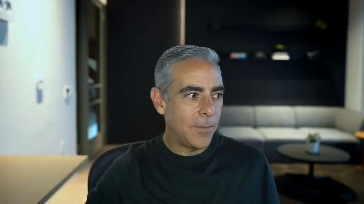The image features a man sitting at a desk with his head tilted back, looking off into the distance or out of focus towards something beyond the frame. The person appears to be an older individual wearing glasses, possibly in front of a couch in what seems to be a living room setting. There are several books scattered around the scene as well. 

The post in question is titled "Former PayPal President David Marcus says Bitcoin is better than gold and predicts it will reach $1,500,000". The main focus of this image is on the man with his glasses sitting at the desk, potentially contemplating or discussing the content related to Bitcoin and its price forecasts.