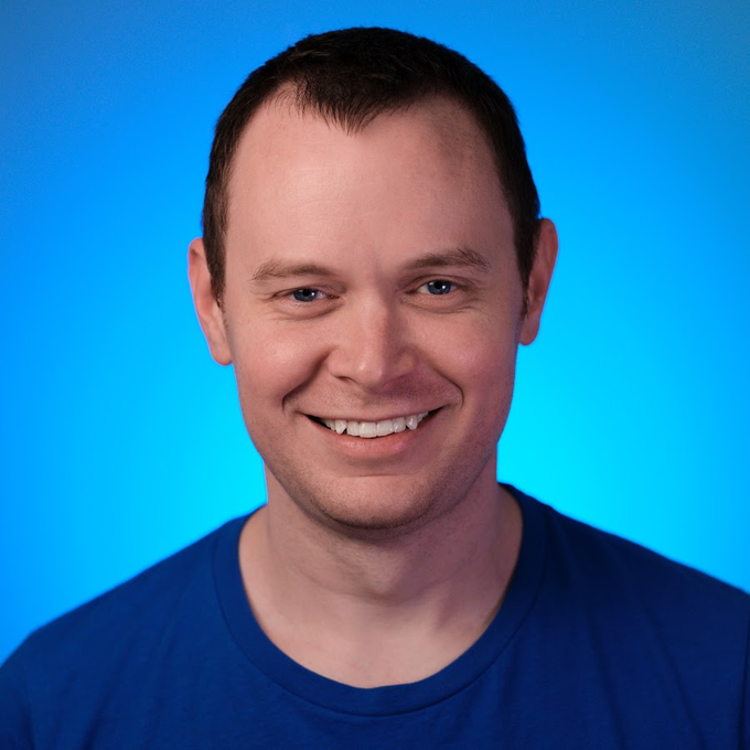 A cheerful man in a blue t-shirt smiles broadly against a blue gradient background, conveying an expression of hopeful anticipation that matches the post's sentiment about being promised a chance to buy Bitcoin in the $40,000s.