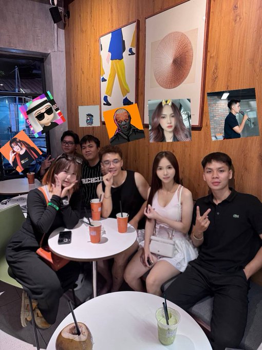A group of young people posing together at what appears to be a social gathering, with their faces covered by various celebrity and character stickers/images, sitting around tables with drinks.