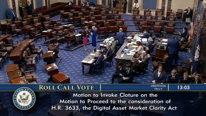 A high-angle view of the U.S. Senate chamber during a 'ROLL CALL VOTE', with on-screen text indicating the 'Motion to Invoke Cloture on the Motion to Proceed to the consideration of H.R. 3633, the Digital Asset Market Clarity Act' at 13:03.