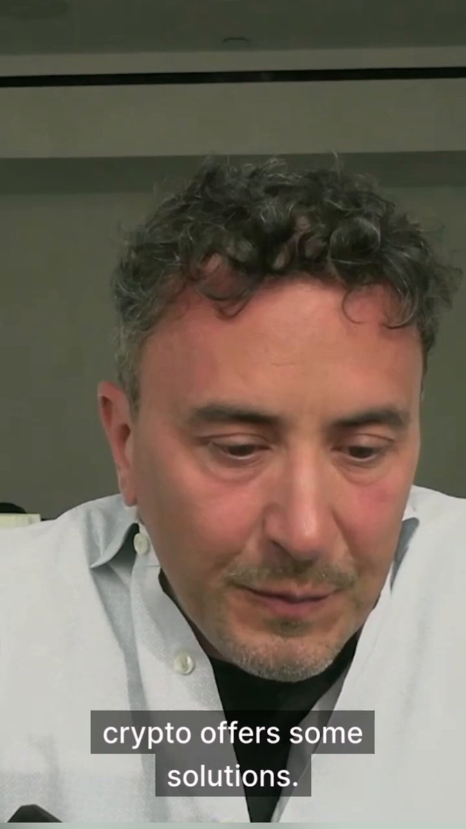 The image features a man with curly hair wearing a white shirt who appears to be looking down at his phone or computer screen. The caption below the image reads "This can be crypto’s moment. @el33th4xor on why transparency and programmable systems matter most in times of turmoil, when people need real solutions." This suggests that there is some sort of discussion or information being shared about cryptocurrency and its impact during challenging times.