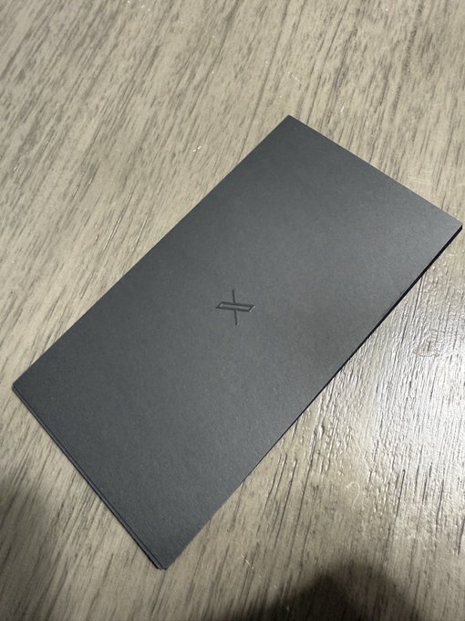 A sleek black rectangular box with an embossed logo on top, resting on a wooden surface.