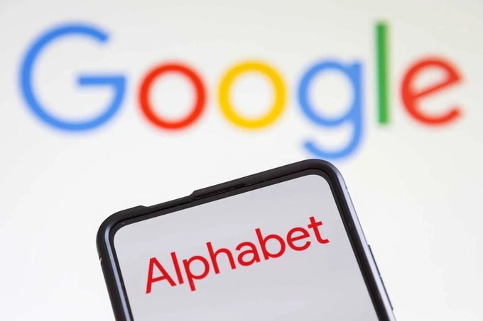 A smartphone displays the word 'Alphabet' in red text against the blurred Google logo background.