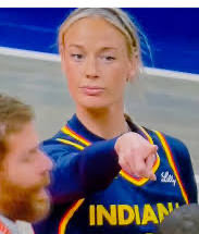 The image shows a young blonde female athlete wearing a navy blue and yellow jacket with "INDIAN" visible on it, pointing forward during what appears to be a sporting event. The connection to the post is ironic and metaphorical—a confident, assertive athlete pointing, paired with text suggesting the benefits of letting people believe a market cycle theory is dead to maintain a competitive edge.