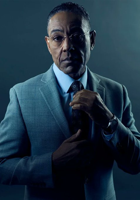A man in a sharp gray suit, blue shirt, and patterned tie adjusts his tie while wearing a wristwatch, set against a moody dark background with dramatic lighting. The professional portrait pairs well with the post's tone of regret and reflection over missed gains on the $NET cryptocurrency token.