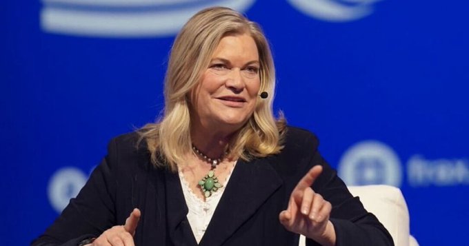 Senator Cynthia Lummis, wearing a black blazer and turquoise squash blossom necklace, speaks at a podium with a headset microphone against a blue backdrop featuring the Milken Institute logo. The image accompanies news of her expressing confidence that the Clarity Act will pass.