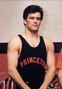 A vintage photograph of a young man wearing a black 'PRINCETON' tank top, possibly from a basketball team, posing against a tiled wall.