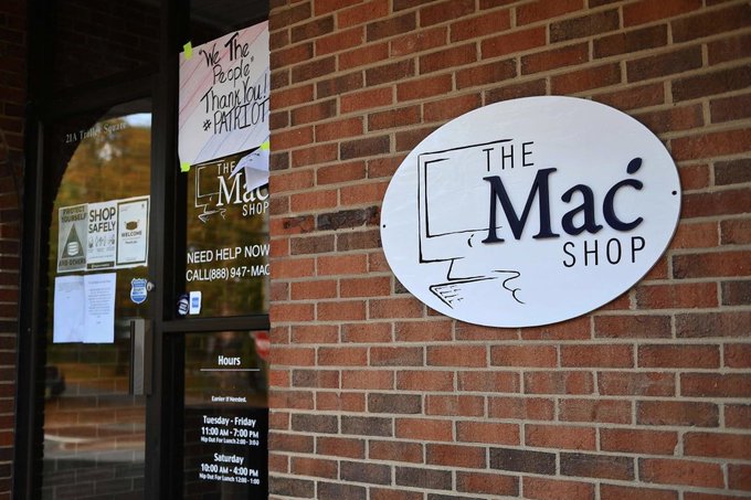 The image shows the storefront of "The Mac Shop," a computer repair business, featuring a circular white sign mounted on a red brick wall and a glass door displaying a "We the People Thank You!" sign, a "Need Help Now" notice with the phone number (888) 947-MAC, and shop hours.

The image of "The Mac Shop" storefront cleverly contrasts with the post's discussion of a failing $LAPTOP token—suggesting that just as a physical computer repair shop would be needed for a "dropped" laptop, the on-chain "laptop" token that was "dropped" again after seven years has predictably crashed, with thin liquidity and a rigged airdrop leaving retail holders holding the bag.