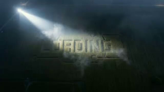 The image features a large, illuminated sign that reads "LOADING" with a spotlight shining down on it. The background of the image shows a dark sky filled with smoke coming from an object or structure. There are no other objects or people visible in the image, and the focus is solely on the sign and its surroundings.