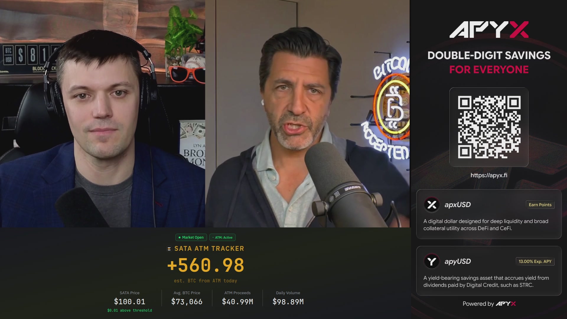 The image shows two men standing behind microphones, with a screen displaying their names and information about cryptocurrency trading on "APYX" that says "Double digit savings for everyone". The background features a plant and other symbols of a trading environment or Bitcoin exchange space.