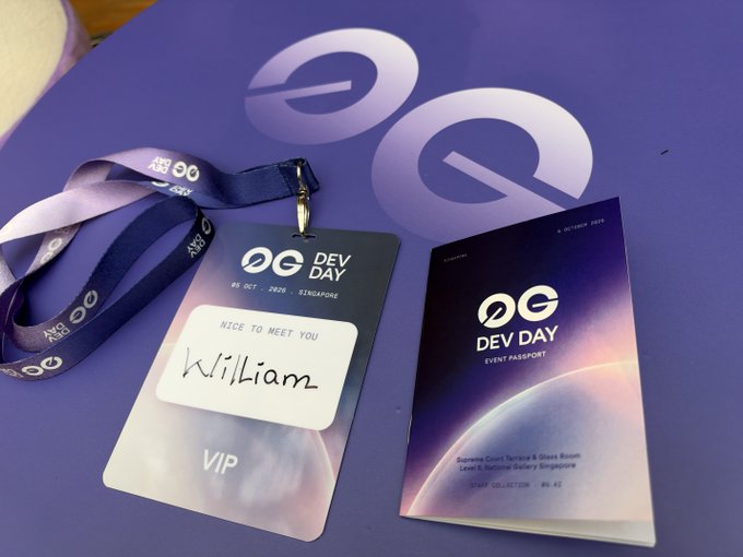 A purple VIP event badge for 'OG DEV DAY' (06 October 2025, Singapore) labeled 'William,' alongside an 'Event Passport' booklet, resting on a matching purple surface.