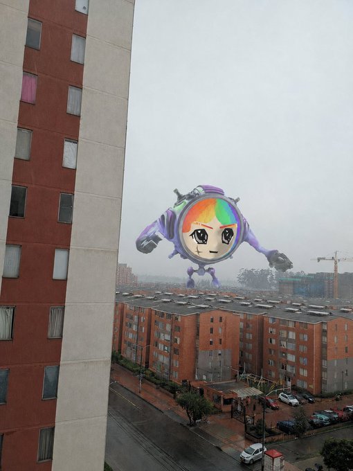 A surreal photo of an apartment complex view where a large purple robot with a rainbow anime-style face looms over the city skyline.