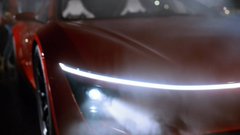 A close-up shot showcases the sleek front end of a red Tesla Roadster, featuring its signature illuminated LED headlights and streamlined hood design, evoking the futuristic aesthetic referenced in the post's "Back to the Future" theme.
