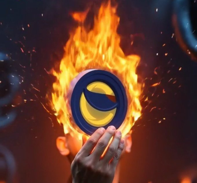 The image features a person's hand holding an illuminated circle of fire against a dark background, with the word "LUNC" written below it in yellow lettering. The caption reads, "More than 448 billion LUNC have been burned since February 2nd,2002. June started with another 32.6 million LUNC burn." It seems to be an artistic or symbolic depiction of a burning LUNC symbol representing the idea that there are many LUNC being burned at once, possibly as part of an ongoing effort to reduce their supply.