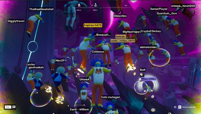 A multiplayer game scene with numerous colorful cartoon-style characters scattered across a vibrant purple and pink environment, with player usernames like 'GamerPlayer', 'Kopirax CATS', 'Quantum_Gun', and 'omega_toxat200' floating above them.