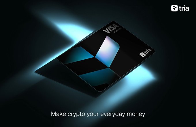 A sleek, dark credit card with a glowing blue 'X' design and the Visa logo rests against a dark background with blue light beams, accompanied by the text "Make crypto your everyday money" and the "tria" logo.
