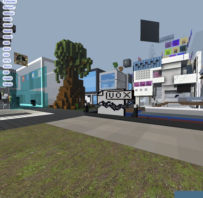 A screenshot from a 3D voxel-based virtual world or game, showing a blocky tree, various UI menu buttons on the left (Fullscreen, Settings, Avatar, etc.), and pixel-art style vehicles in the background.