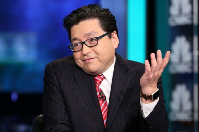 A man wearing a pinstripe suit, red striped tie, and glasses gestures with his hand while speaking on what appears to be a financial news set. He fits the context of the post discussing Tom Lee's insights on the ETH/BTC ratio as a signal for crypto recovery.