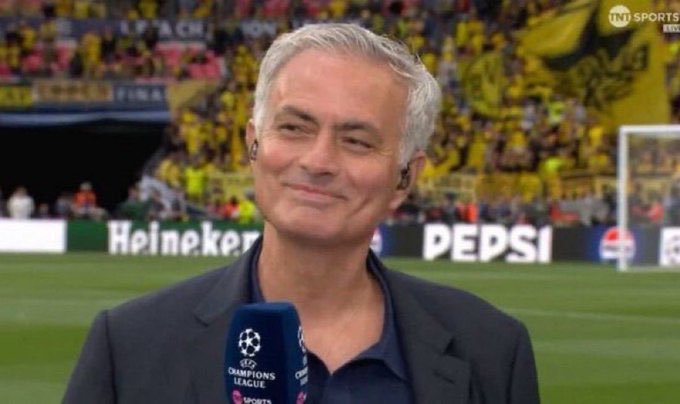 Football manager José Mourinho smiles during a TNT Sports interview on a pitch, with 'Heineken' and 'PEPSI' advertising boards and a Champions League microphone visible.